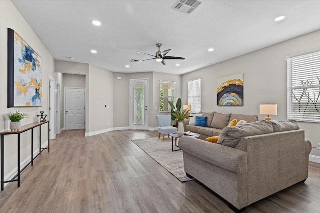 living room with visible vents, baseboards, recessed lighting, wood finished floors, and a textured ceiling