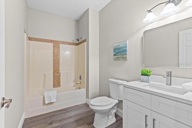 bathroom with toilet, shower / tub combination, wood finished floors, baseboards, and vanity