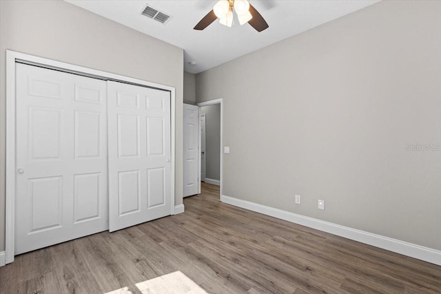 unfurnished bedroom featuring visible vents, baseboards, a closet, and wood finished floors