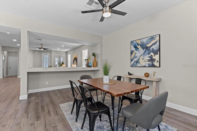 dining area featuring visible vents, baseboards, wood finished floors, a textured ceiling, and a ceiling fan