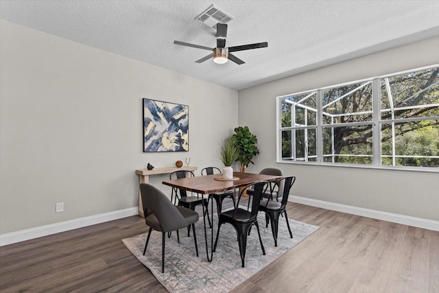 dining room with visible vents, baseboards, a textured ceiling, and wood finished floors