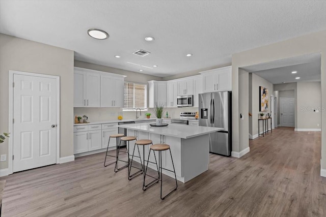 kitchen with a center island, visible vents, white cabinetry, and stainless steel appliances