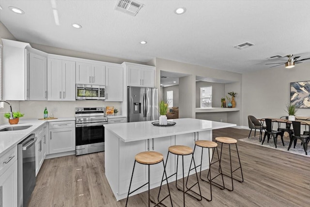 kitchen featuring light wood finished floors, visible vents, appliances with stainless steel finishes, and a sink