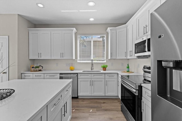 kitchen featuring white cabinets, appliances with stainless steel finishes, light countertops, and a sink