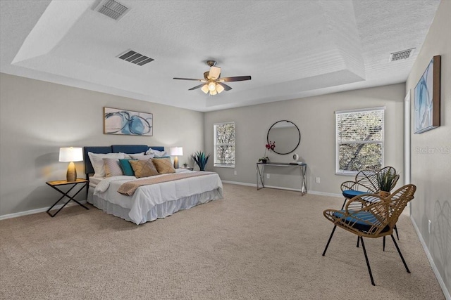 bedroom featuring visible vents, carpet flooring, a textured ceiling, and a tray ceiling