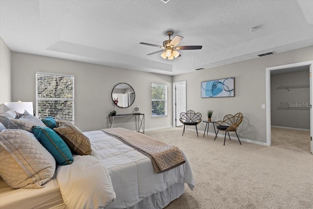 carpeted bedroom featuring a tray ceiling, baseboards, a textured ceiling, and visible vents