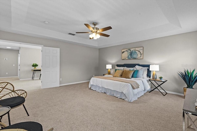 bedroom featuring light carpet, visible vents, a raised ceiling, and baseboards