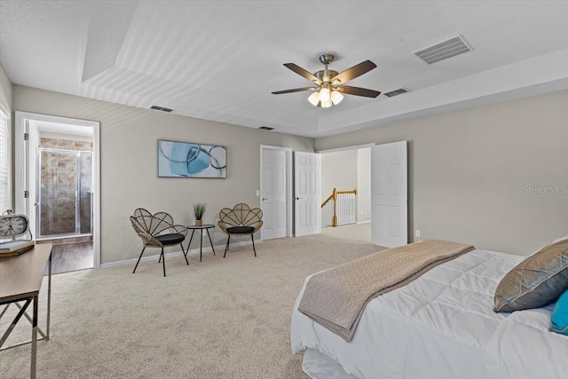 carpeted bedroom with a tray ceiling, visible vents, and baseboards