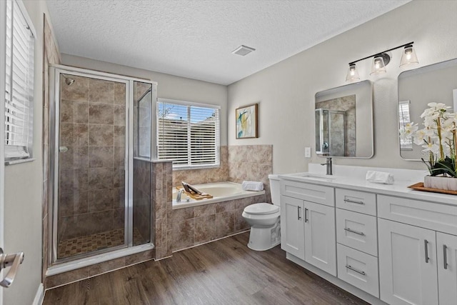 bathroom with visible vents, a shower stall, a garden tub, and wood finished floors