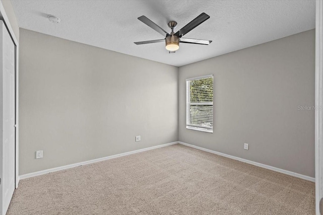 carpeted spare room with a textured ceiling, baseboards, and a ceiling fan