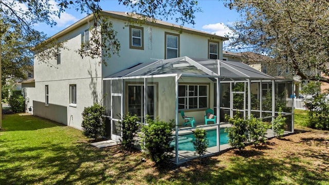 back of property with fence, a lanai, stucco siding, a lawn, and an outdoor pool