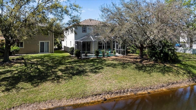 rear view of property with a lanai, a yard, a water view, and stucco siding