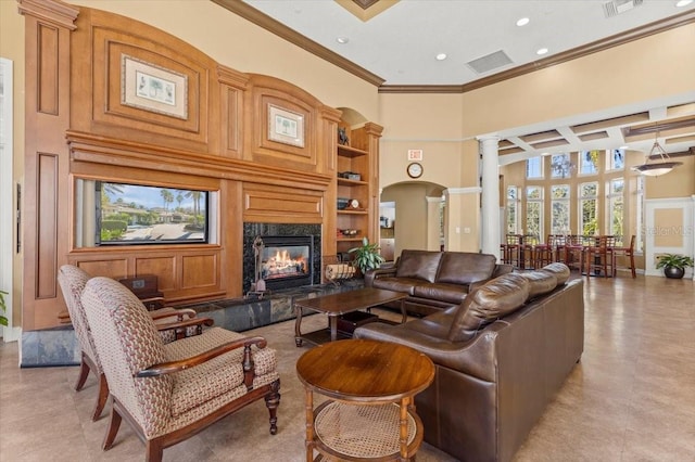 living area with decorative columns, a healthy amount of sunlight, a towering ceiling, and a fireplace