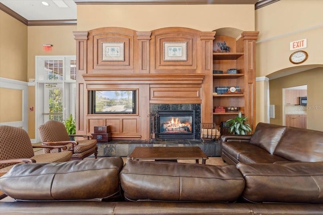 living room featuring a premium fireplace, arched walkways, built in shelves, and crown molding