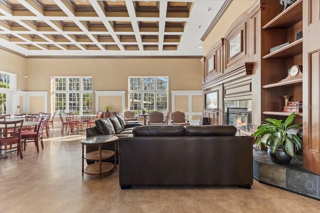 living area featuring a glass covered fireplace, beamed ceiling, crown molding, and a high ceiling