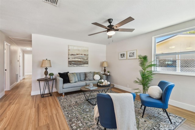 living room featuring baseboards, wood finished floors, visible vents, and ceiling fan