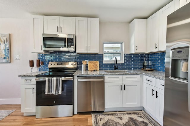 kitchen featuring a sink, light stone counters, white cabinetry, and stainless steel appliances