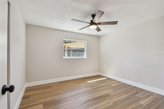 unfurnished room with a textured wall, a textured ceiling, baseboards, and wood finished floors