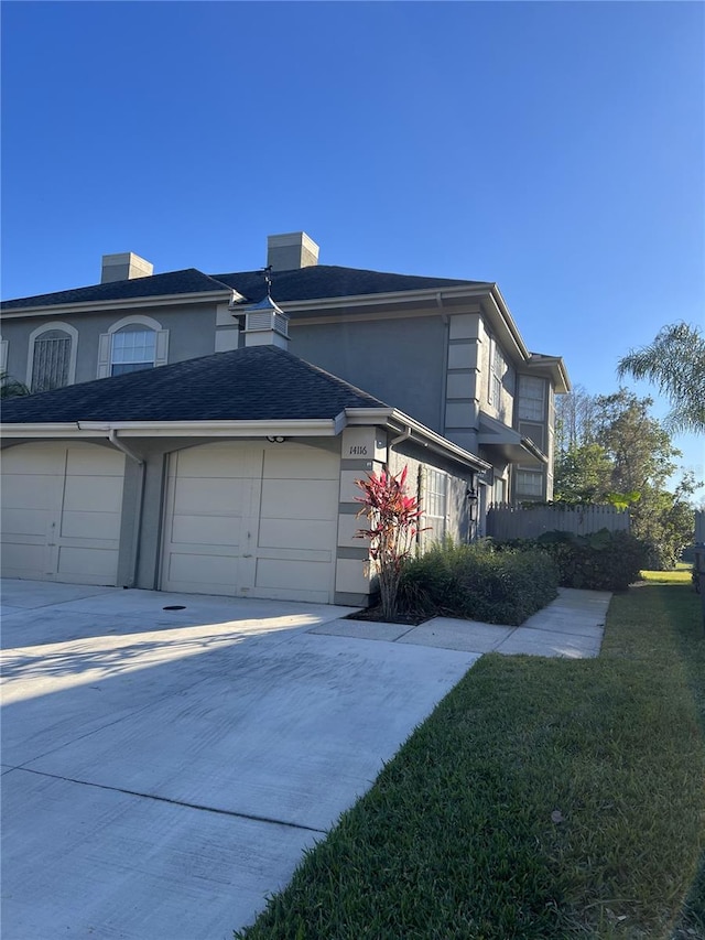 view of side of property with stucco siding, concrete driveway, and a yard