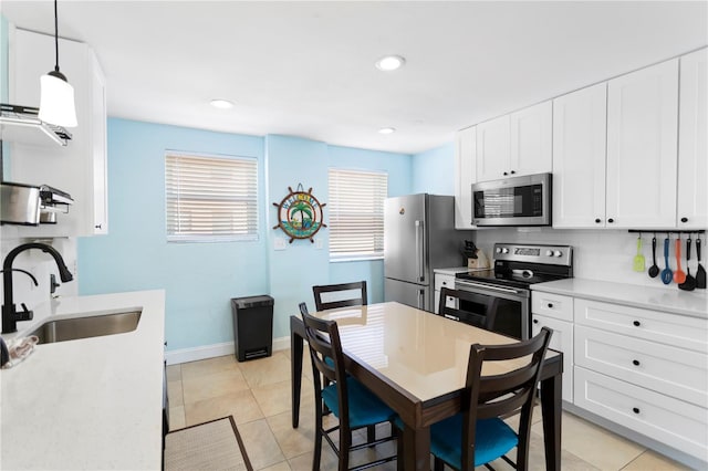 kitchen with a sink, decorative backsplash, light countertops, white cabinets, and appliances with stainless steel finishes