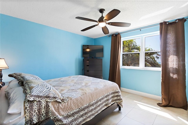 bedroom with tile patterned floors, a ceiling fan, baseboards, and a textured ceiling