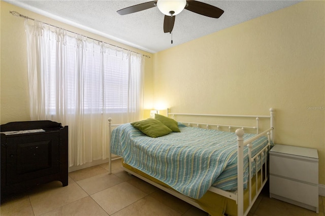 tiled bedroom with a ceiling fan and a textured ceiling