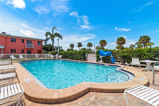 pool with a patio area and fence