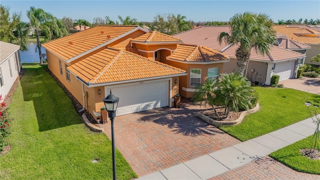 mediterranean / spanish house featuring a garage, decorative driveway, stucco siding, and a tiled roof