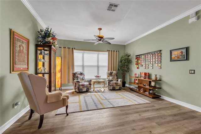 sitting room with crown molding, wood finished floors, visible vents, and baseboards