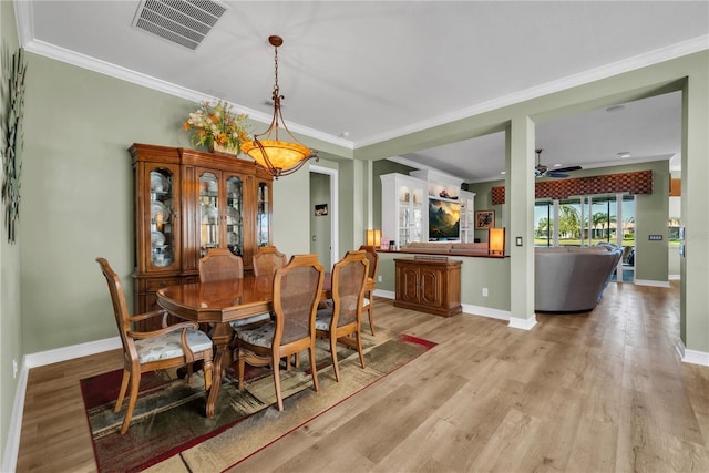 dining area featuring visible vents, crown molding, light wood finished floors, baseboards, and ceiling fan