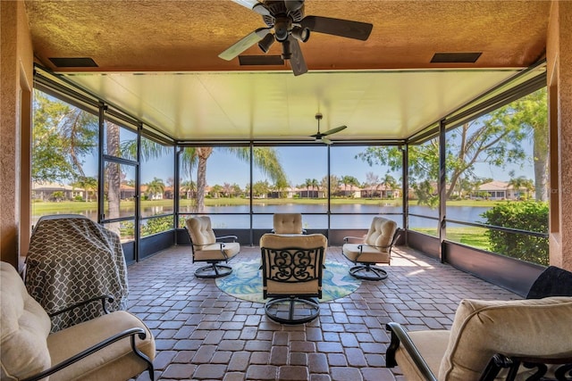 sunroom featuring a wealth of natural light, ceiling fan, and a water view