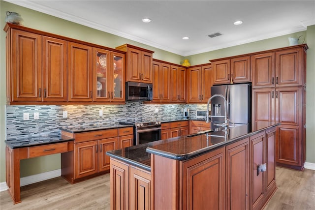 kitchen with visible vents, light wood-style flooring, stainless steel appliances, brown cabinetry, and built in study area