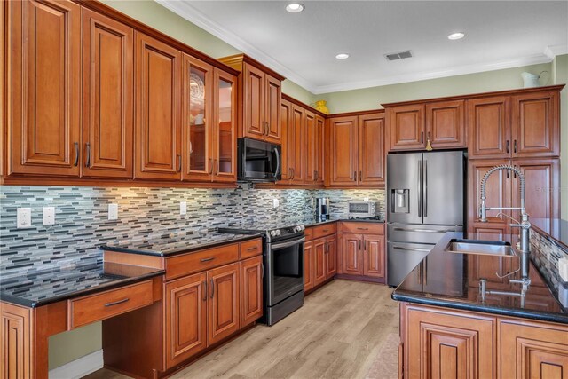 kitchen with brown cabinetry, visible vents, a sink, ornamental molding, and stainless steel appliances