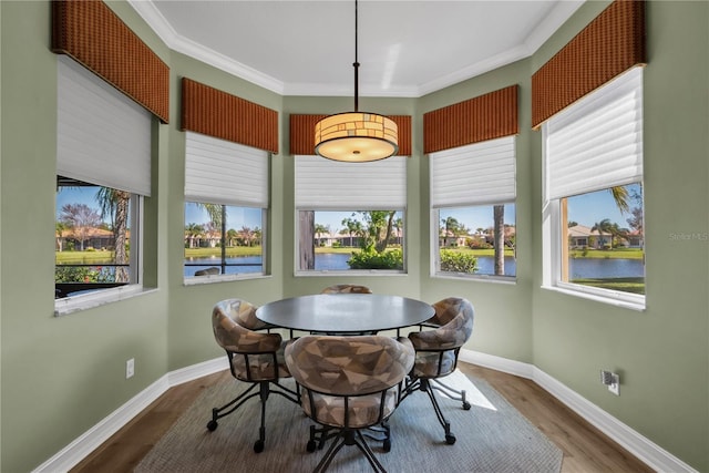 dining room featuring plenty of natural light, wood finished floors, crown molding, and a water view