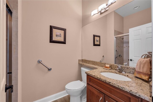 bathroom with vanity, a shower stall, toilet, and baseboards