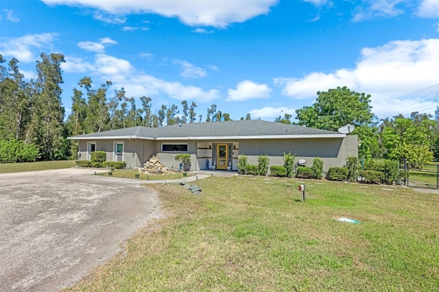 single story home with stucco siding, dirt driveway, and a front yard