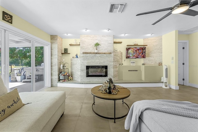 living room featuring visible vents, baseboards, a stone fireplace, and ceiling fan