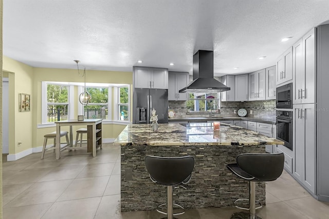 kitchen featuring tasteful backsplash, exhaust hood, gray cabinets, and stainless steel appliances