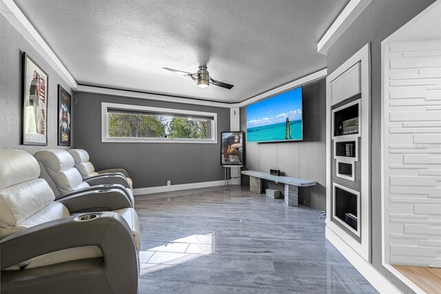 living room featuring wood finished floors, a ceiling fan, baseboards, and a textured ceiling