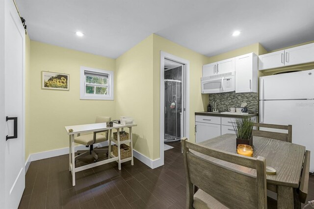 kitchen featuring dark wood finished floors, decorative backsplash, white appliances, and white cabinetry