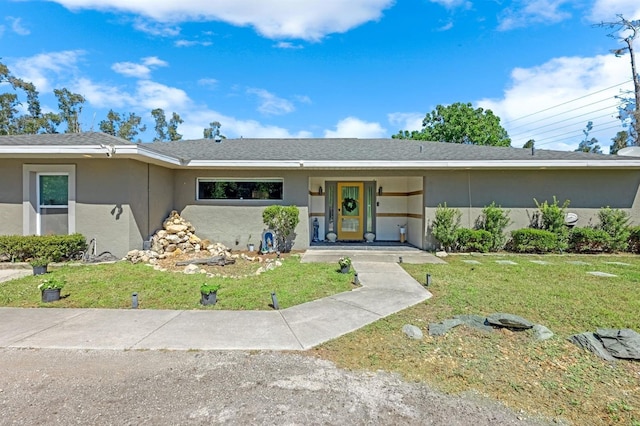 view of front of property featuring stucco siding, a front yard, and roof with shingles