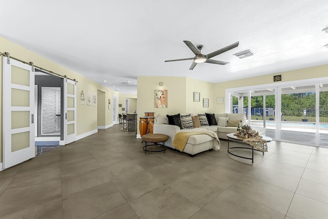 living room with visible vents, a barn door, and a ceiling fan