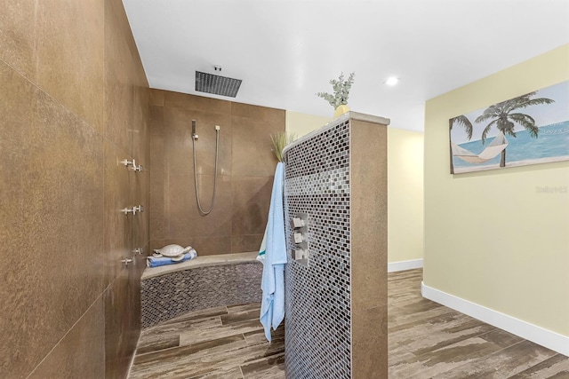 full bathroom featuring wood finished floors, baseboards, and a tile shower