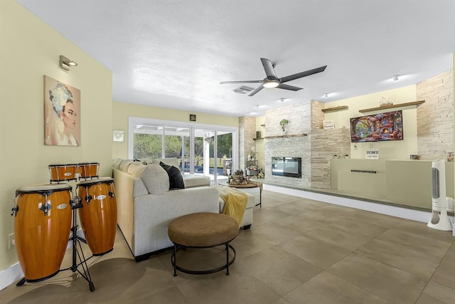 living area with a stone fireplace, visible vents, and ceiling fan