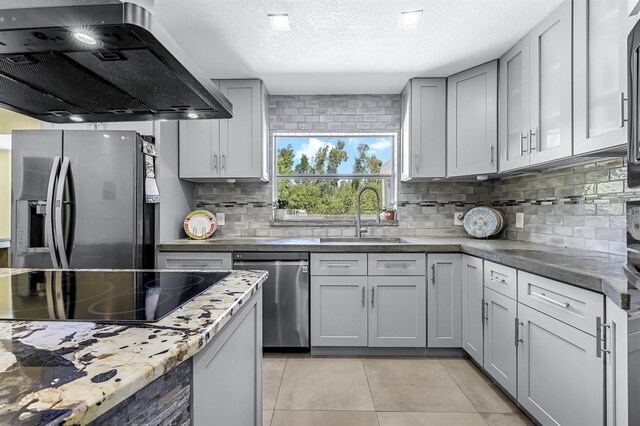 kitchen with a sink, stainless steel appliances, exhaust hood, light tile patterned floors, and decorative backsplash