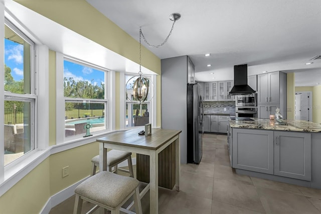 kitchen with decorative backsplash, gray cabinetry, exhaust hood, and appliances with stainless steel finishes