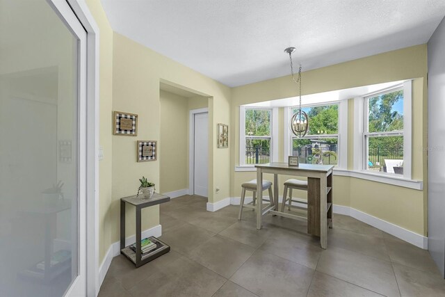 dining space featuring tile patterned flooring, an inviting chandelier, and baseboards