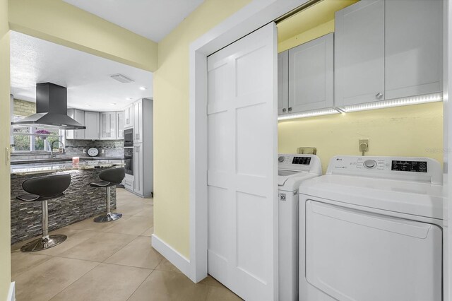 laundry room featuring visible vents, washer and dryer, cabinet space, light tile patterned floors, and baseboards