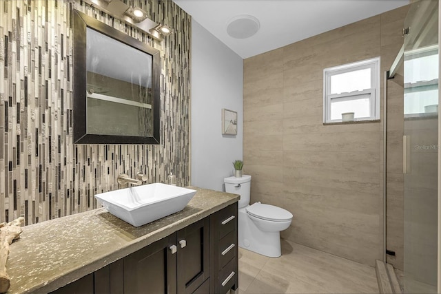 bathroom with vanity, a shower stall, tile walls, toilet, and tile patterned floors