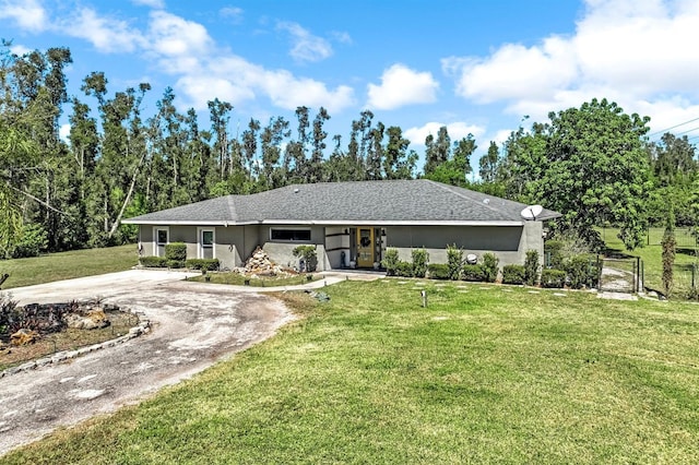 ranch-style home featuring stucco siding, dirt driveway, roof with shingles, and a front yard